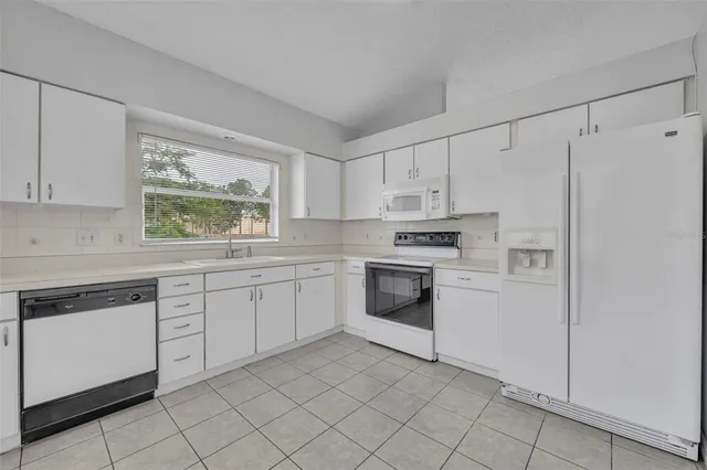 a kitchen with white cabinets stainless steel appliances and window
