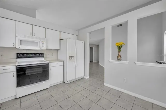 a kitchen with white cabinets and appliances