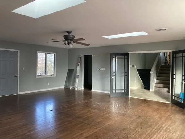a view of an empty room with a window and wooden floor