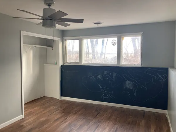 a view of an empty room with a window and wooden floor