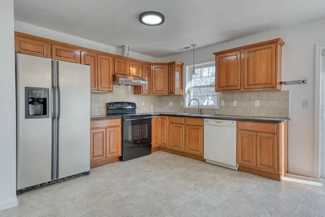 a kitchen with granite countertop stainless steel appliances a refrigerator stove top oven and sink