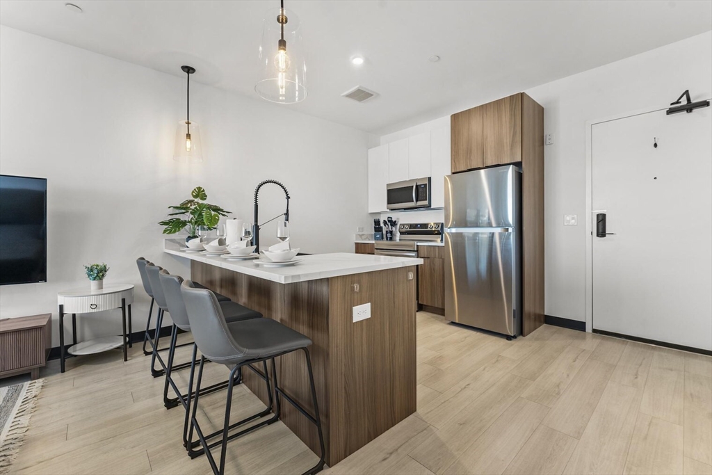 a kitchen with stainless steel appliances a dining table chairs refrigerator and microwave