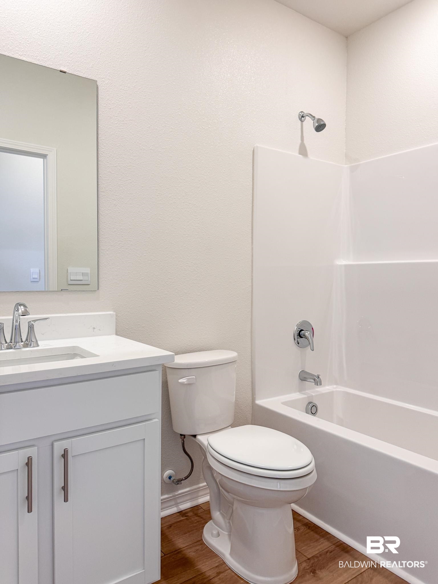 18151 Kent Circle Foley, AL 36535 - Photo 15 of 25 Full bathroom featuring a white vanity with integrated sink, chrome faucet, wood-finish flooring, white toilet, and a combined shower-bathtub unit with white surround