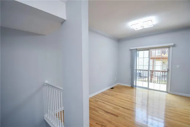 a view of an empty room with wooden floor and closet