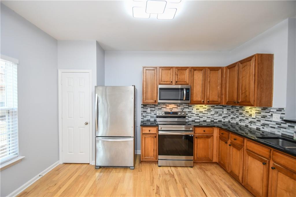 2201 Landing Walk Drive Duluth, GA 30097 - Photo 40 of 80 a kitchen with stainless steel appliances granite countertop a refrigerator stove a sink and dishwasher with wooden floor