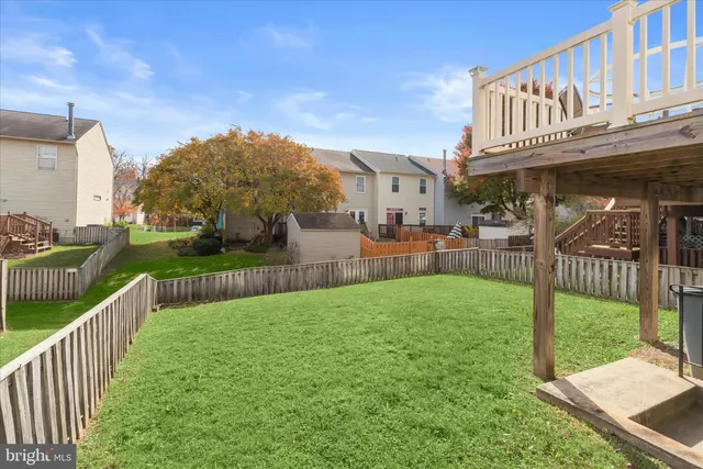 a view of a white house with a big yard and wooden fence