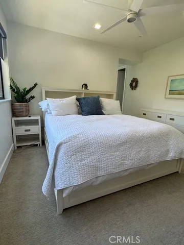 a bedroom with a bed and a potted plant on the dresser