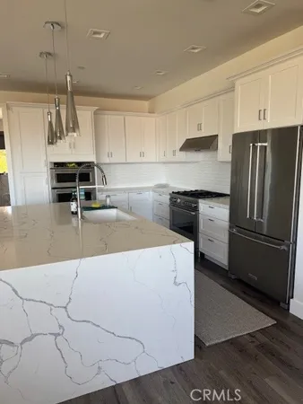 a kitchen with kitchen island a counter top space a sink stainless steel appliances and cabinets