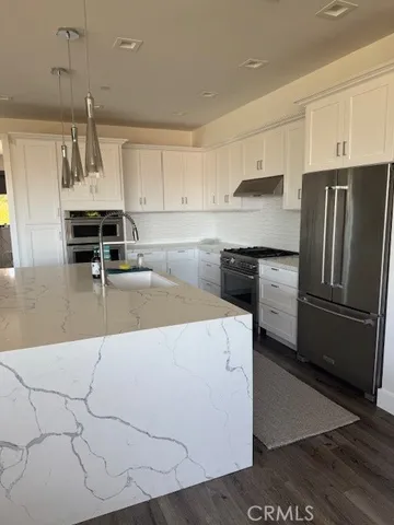a kitchen with kitchen island a counter top space a sink stainless steel appliances and cabinets