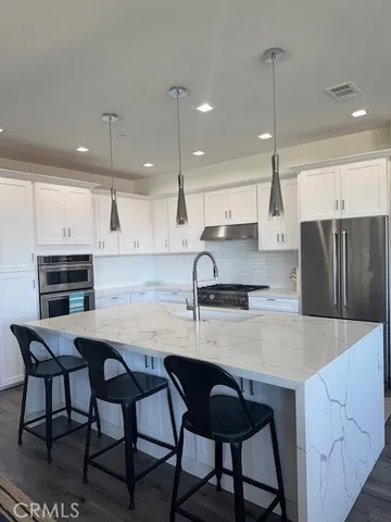 a kitchen with stainless steel appliances granite countertop a table chairs sink refrigerator and microwave