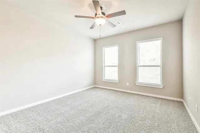 an empty room with windows and fan