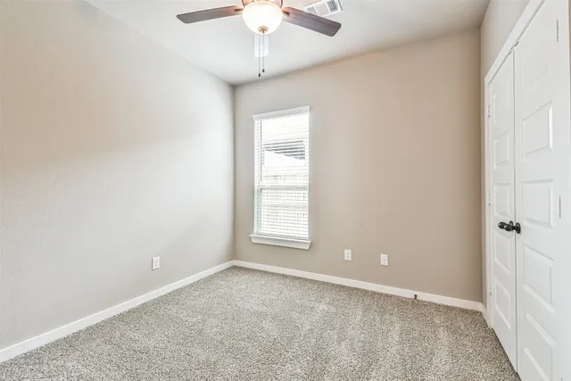 an empty room with a chandelier fan and windows