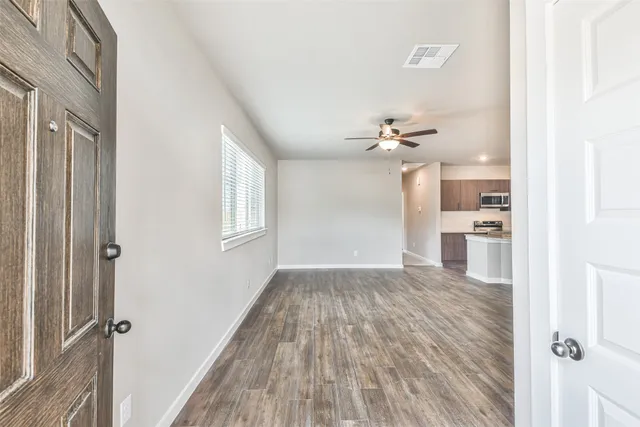 a view of a hallway with wooden floor and a bathroom