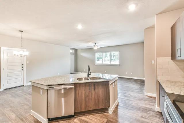 a kitchen with granite countertop a sink cabinets and wooden floor