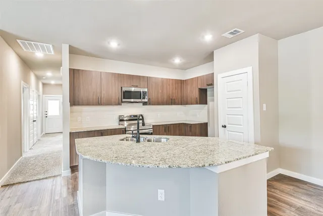 a kitchen with kitchen island granite countertop a sink and refrigerator
