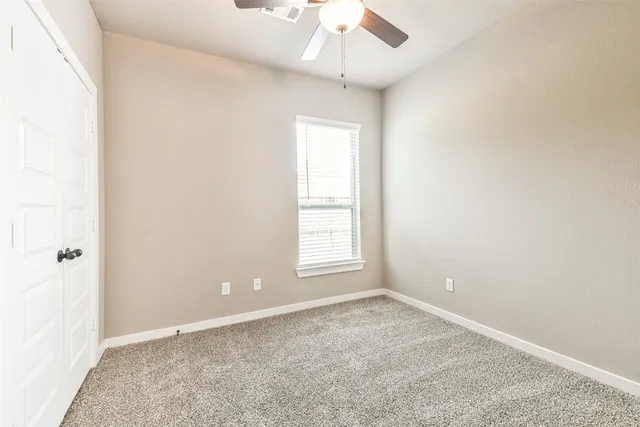 an empty room with a window and a chandelier fan