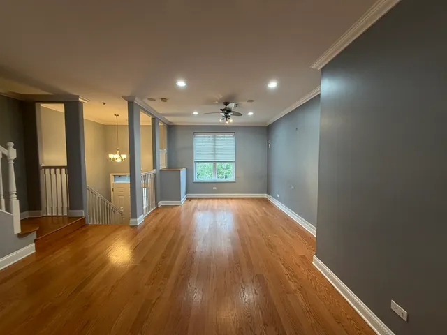 a view of empty room with wooden floor and fan