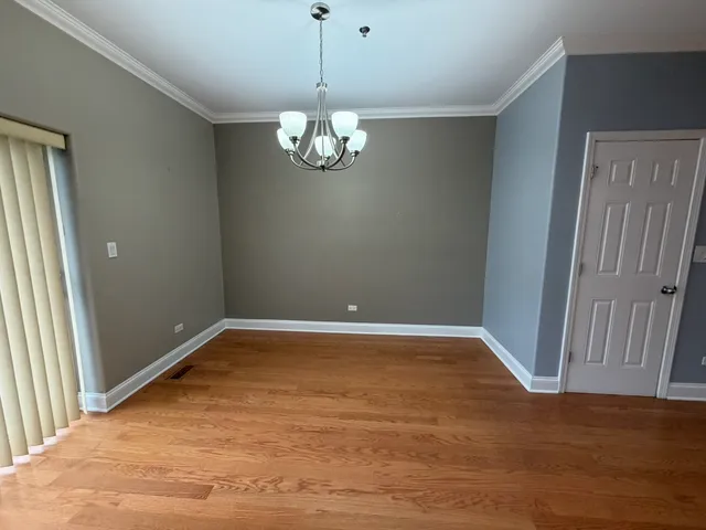 an empty room with wooden floor and chandelier