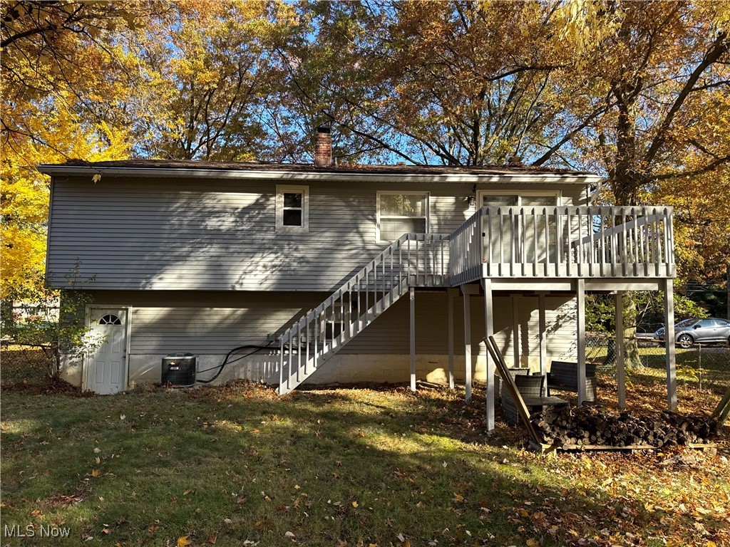 Rear view of property with a yard, a deck, and central AC unit