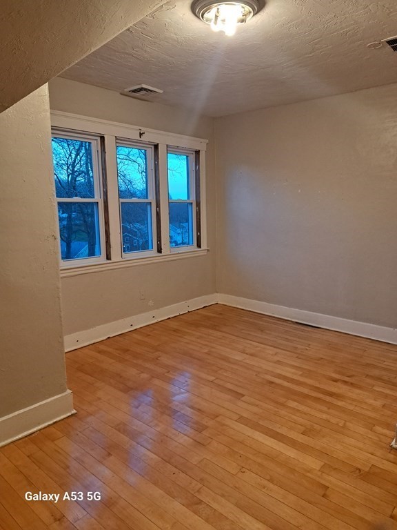 98 Brookline Street, Unit 1 Worcester, MA 01603 - Photo 16 of 18 an empty room with wooden floor and windows