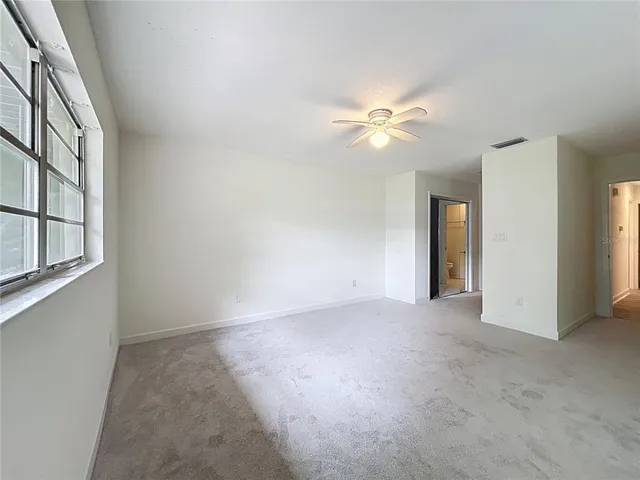 an empty room with fan and windows