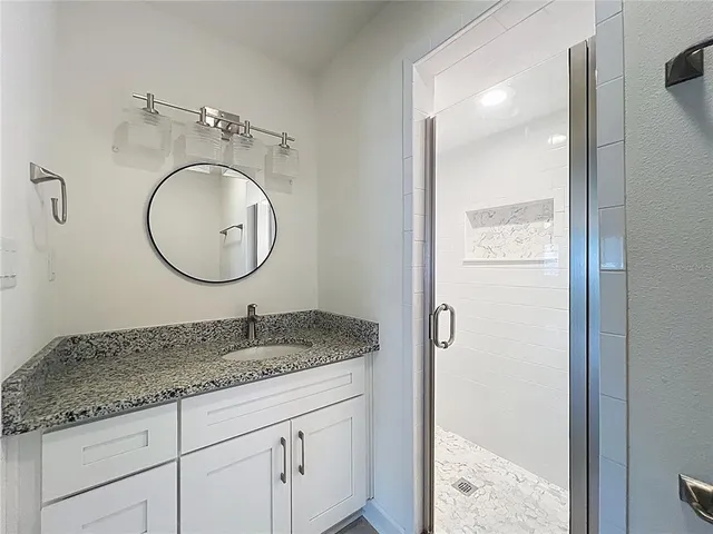 a bathroom with a granite countertop sink and a mirror
