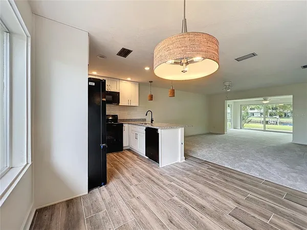 a kitchen with stainless steel appliances granite countertop a refrigerator a sink dishwasher a stove and white countertops with wooden floor