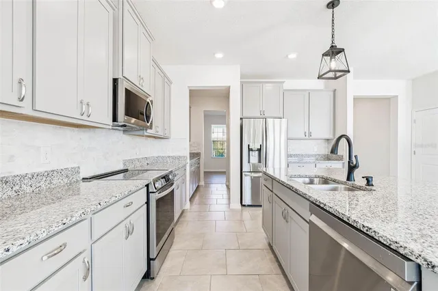 a kitchen with stainless steel appliances granite countertop white cabinets and window