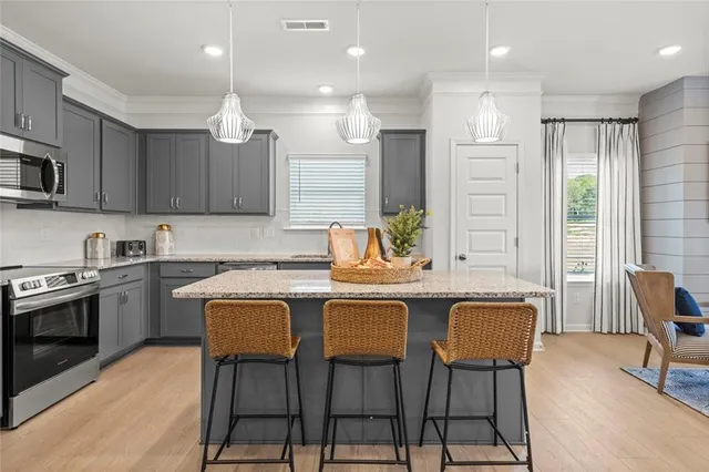 a kitchen with stainless steel appliances kitchen island granite countertop a table chairs sink and cabinets