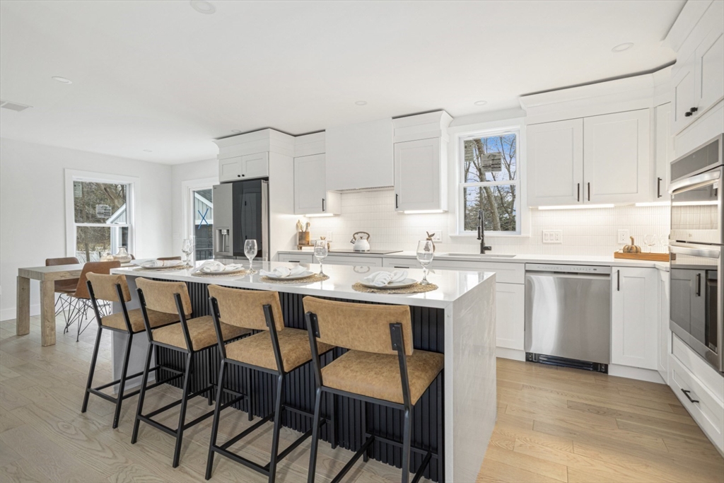 63 Kellogg Street Framingham, MA 01701 - Photo 8 of 38 a kitchen with a dining table chairs and white cabinets