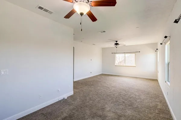 an empty room with windows fireplace and a kitchen view