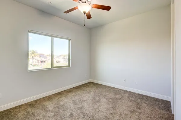 an empty room with a window and a fan