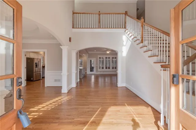a view of an empty room with wooden floor and a kitchen