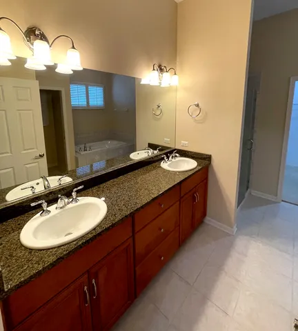 a bathroom with a granite countertop double vanity sink and a mirror
