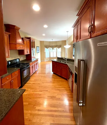 a kitchen with stainless steel appliances granite countertop a refrigerator a stove and a sink