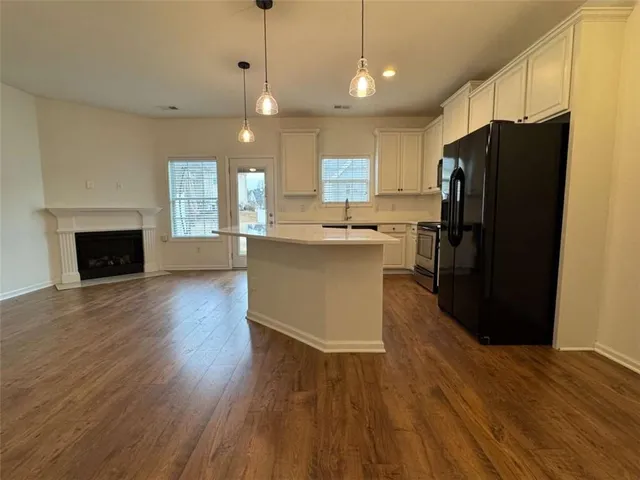 a kitchen with stainless steel appliances granite countertop a refrigerator a stove top oven a sink dishwasher and a refrigerator with wooden floor