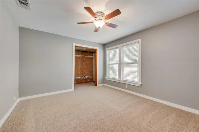 an empty room with closet and ceiling fan