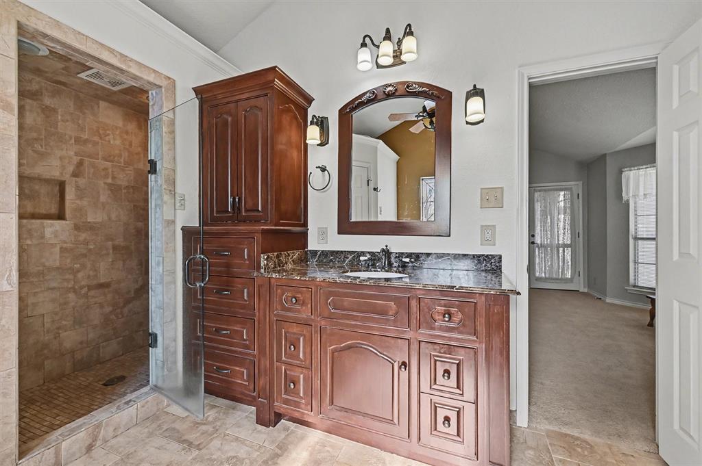 304 Trollinger Street Whitesboro, TX 76273 - Photo 15 of 25 a bathroom with a granite countertop sink a mirror and a shower