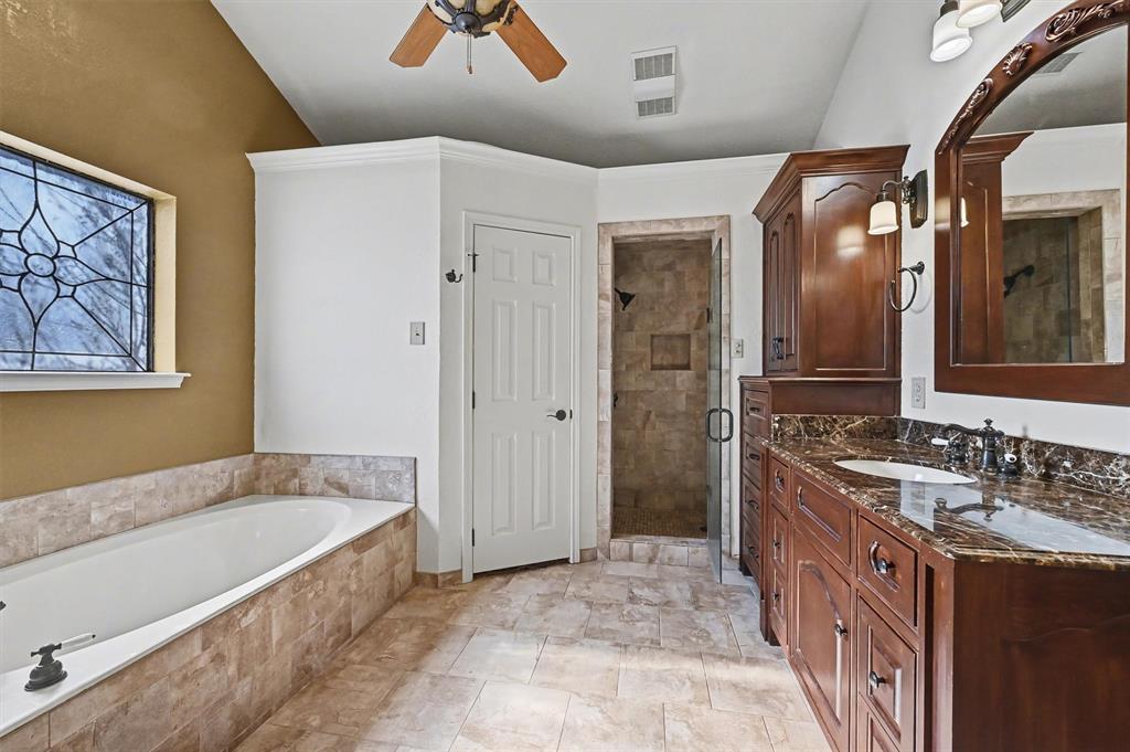 304 Trollinger Street Whitesboro, TX 76273 - Photo 16 of 25 a spacious bathroom with a granite countertop tub sink and mirror