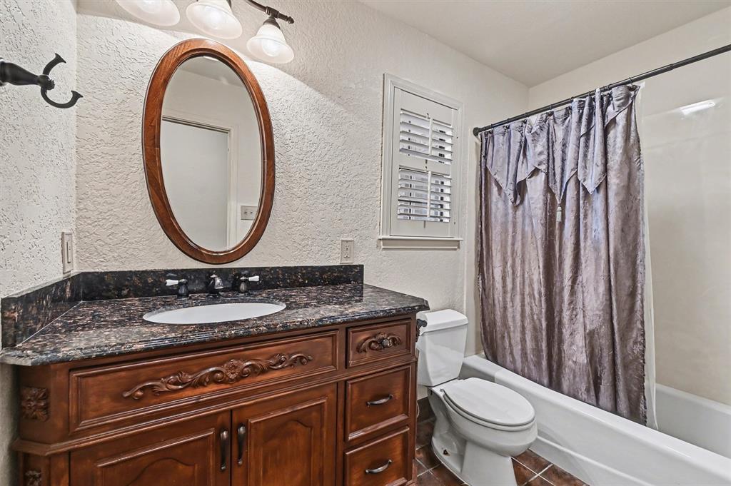 304 Trollinger Street Whitesboro, TX 76273 - Photo 20 of 25 a bathroom with a granite countertop toilet a sink and a mirror