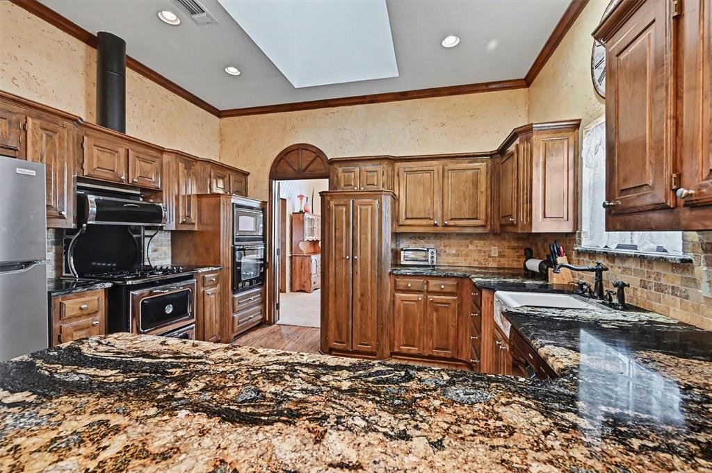 304 Trollinger Street Whitesboro, TX 76273 - Photo 4 of 25 a kitchen with stainless steel appliances granite countertop a refrigerator stove top oven and sink