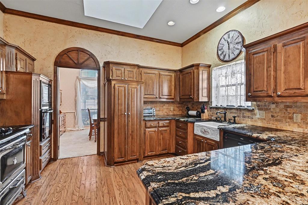 304 Trollinger Street Whitesboro, TX 76273 - Photo 7 of 25 a kitchen with stainless steel appliances granite countertop a stove a refrigerator and a stove top oven with wooden floor