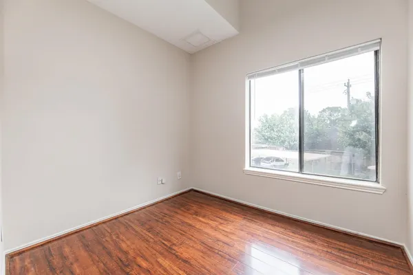 an empty room with wooden floor fireplace and windows