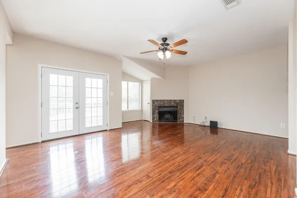 a view of an empty room with wooden floor and a fireplace