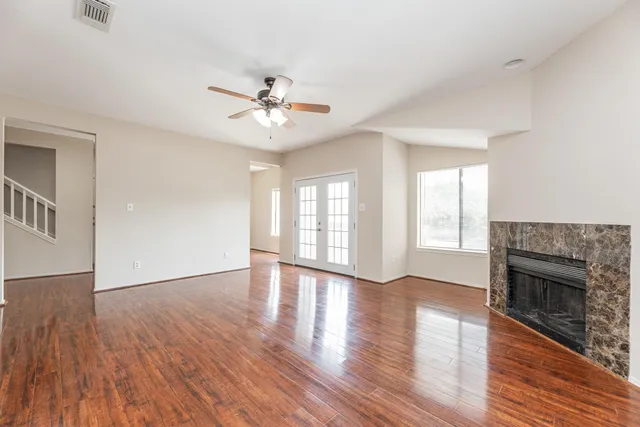 a view of empty room with wooden floor and ceiling fan