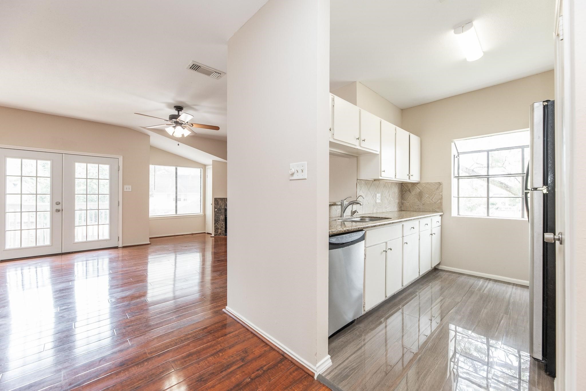 2023 Gentryside Drive, Unit 508 Houston, TX 77077 - Photo 20 of 41 a kitchen with granite countertop a stove a sink and white cabinets with wooden floor