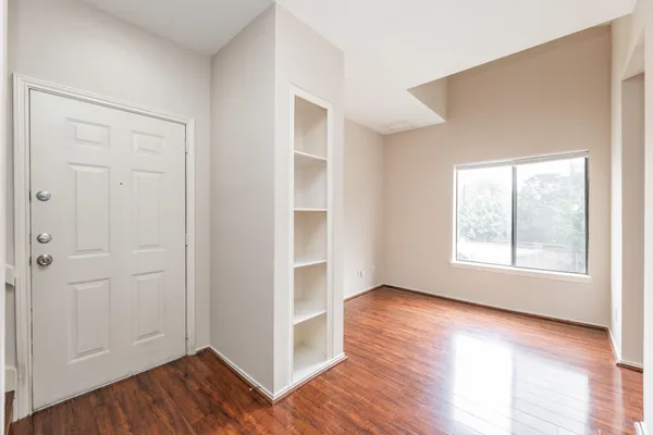 an empty room with wooden floor and windows