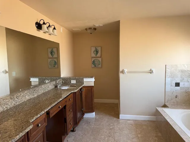 a bathroom with a granite countertop sink a mirror and a shower