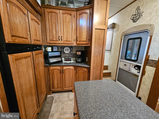 a open kitchen with stainless steel appliances granite countertop a stove a refrigerator a couch and a dining table with wooden floor