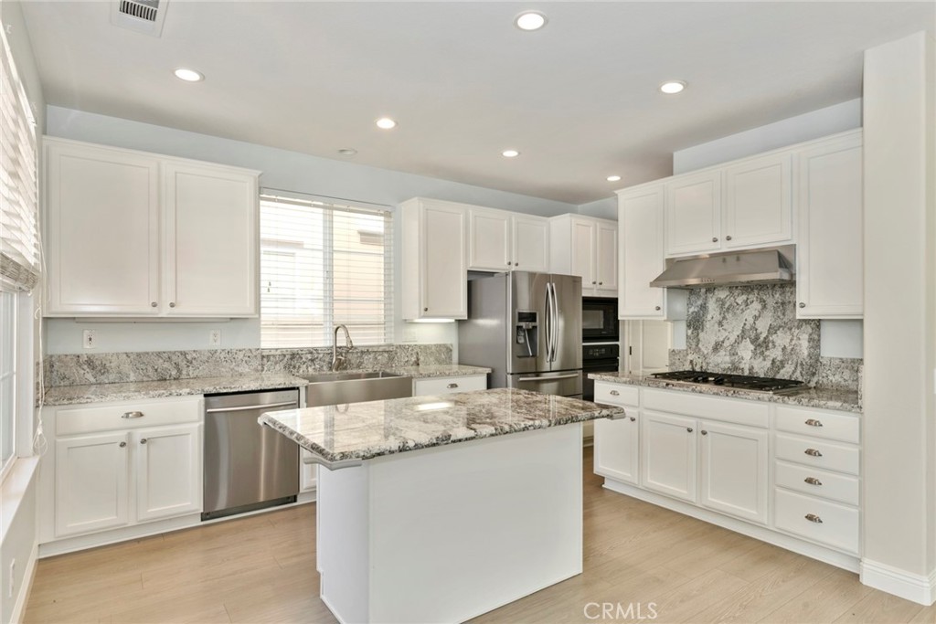 63 Figtree Irvine, CA 92603 - Photo 4 of 14 a kitchen with granite countertop white cabinets sink and stainless steel appliances